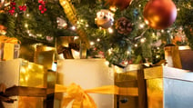 Assorted gold and brown presents neatly arranged under a festive Christmas tree.