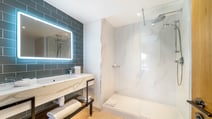 Render of a bathroom within a bedroom at The Runnymede on Thames hotel, including a shower and back-lit mirror