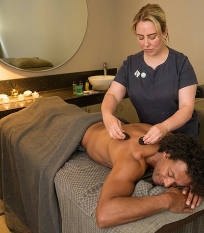 A guest receiving a stone massage spa treatment at Studley Castle's Stables Spa