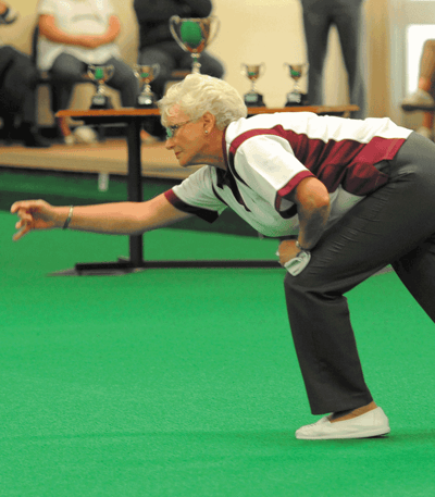 With a smile on her face, a woman leans forward to throw a ball and having a great time playing bowls at a Warner hotel.