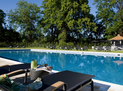 The outdoor pool and lounger at The Runnymede on Thames Hotel, with a cocktail being enjoyed by a guest