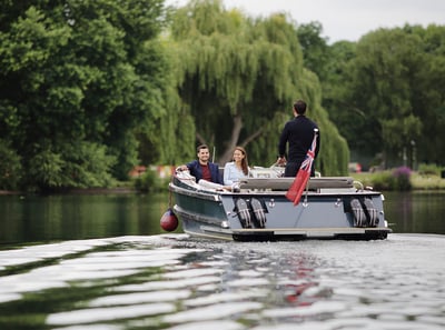 A pair of guests enjoying a boat ride along the River Thames, skippered by a team member at The Runnymede on Thames Hotel