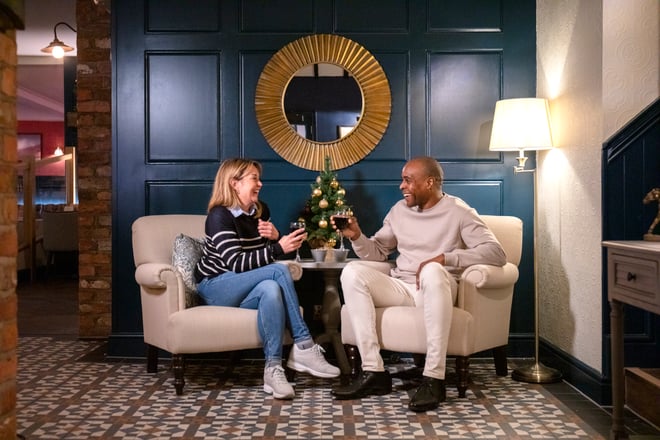 Couple enjoying festive drinks in front of a Christmas Tree